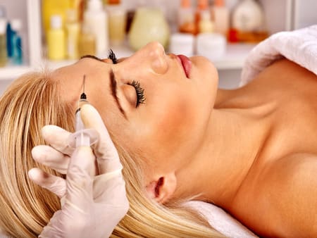 39838179 - beauty woman giving botox injections on forehead.
