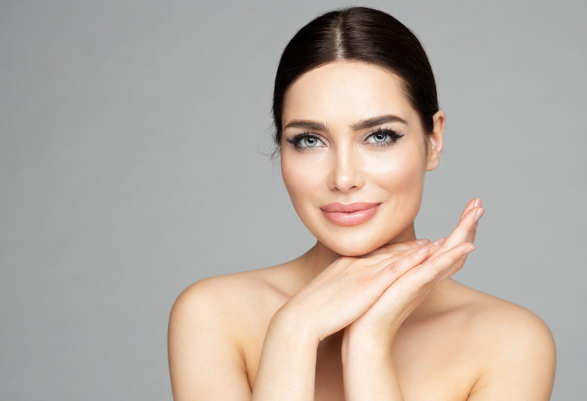Beauty Woman Face Skin Care. Beautiful Woman Portrait with Full Lips and Long Eyelashes over Gray. Hands Manicure and Facial Treatment Cosmetics. Spa Massage and Face Lift Cosmetology Chemical Peels in McLean, VA